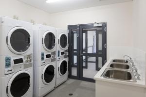 eine Waschküche mit drei Waschmaschinen und einem Waschbecken in der Unterkunft Fremantle Prison YHA in Fremantle