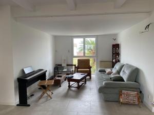 een woonkamer met een bank en een piano bij Villa familiale à Sète in Sète