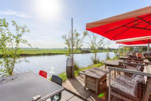 un tavolo da picnic con ombrellone rosso accanto a un fiume di Hajé Nieuwegein a Nieuwegein