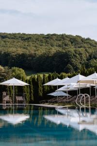 a swimming pool with white umbrellas and a pool at Schlössl Hotel Kindl in Bad Gleichenberg