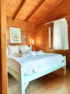 a bedroom with a white bed in a wooden room at Eden Ramot Chalets in Moshav Ramot