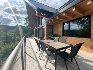 une terrasse en bois avec une table et des chaises sur une maison dans l'établissement Le Harfång - Vue spectaculaire sur le Mont Edouard, à LʼAnse-Saint-Jean