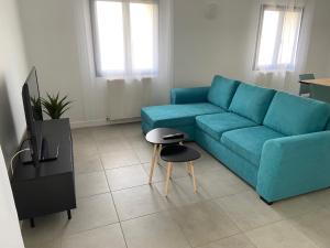 a living room with a blue couch and a tv at Maison de vacances avec piscine et jardin privé in Lherm