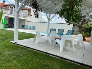 - un ensemble de chaises blanches et d'une table sur une terrasse dans l'établissement Jolie maison proche de Toulouse, à Lherm