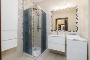 een badkamer met een douche, een wastafel en een spiegel bij Stary Browar Półwiejska Apartment with AC by Renters in Poznań