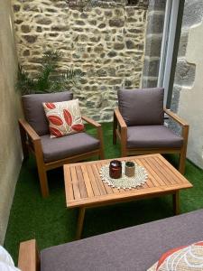 2 Stühle und ein Couchtisch auf einer Terrasse in der Unterkunft Granville / Maison entièrement rénovée à 100 m des plages in Granville