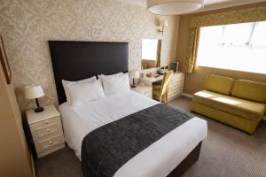 Millers Hotel by Greene King Inns في Sibson: غرفة فندقية بسرير كبير وكرسي