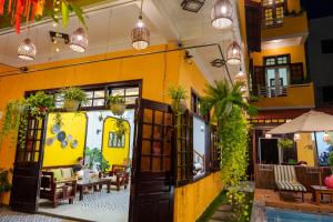 a restaurant with yellow walls and potted plants at Thien Tan Villa with Private Pool in Hoi An