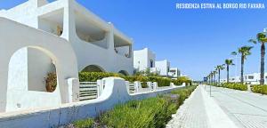 a white building next to a street with palm trees at Residenza estiva al Borgo Rio Favara in Santa Maria Del Focallo