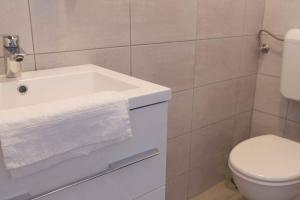 ein Badezimmer mit einem weißen Waschbecken und einem WC in der Unterkunft Apartments in Bük - Nordtransdanubien 44085 in Bük