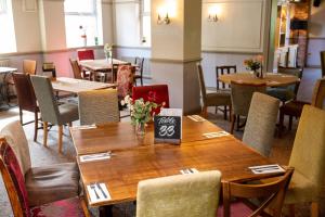 - une salle à manger avec une table et des fleurs dans l'établissement Millers Hotel by Greene King Inns, à Sibson