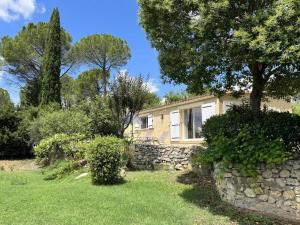 ein Steinhaus mit einer Steinmauer und Bäumen in der Unterkunft Le Mas Bello Visto in Lorgues