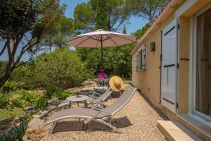 eine Terrasse mit einem Tisch und einem Sonnenschirm in der Unterkunft Le Mas Bello Visto in Lorgues