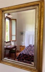 specchio che riflette una camera da letto con letto e tavolo di Casa le Rondini Toscana a Bucine