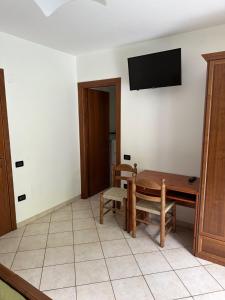 a living room with a table and a tv on the wall at Locanda Fungo Reale in Valloriate
