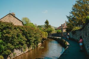 um rio ao lado de uma parede com pessoas andando ao longo dele em Swallow Cottage, Bakewell em Bakewell