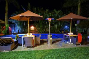 two tables and umbrellas next to a pool at night at The Bedelle in Nairobi