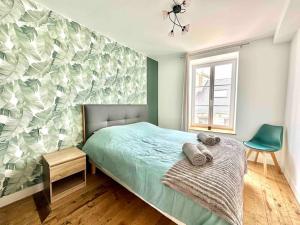 een slaapkamer met een bed en een groene muur bij Le Nid Douillet Cherbourgeois in Cherbourg en Cotentin