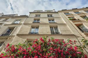 un edificio alto con flores rosas delante en Apartment Notre Dame de Paris by Studio prestige en París