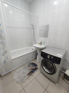 uma casa de banho com uma máquina de lavar roupa e um lavatório em Апартаменты в новостройке по Байзакова 131/1 em Pavlodar