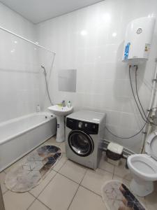 een badkamer met een wasmachine en een wastafel bij Апартаменты в новостройке по Байзакова 131/1 in Pavlodar