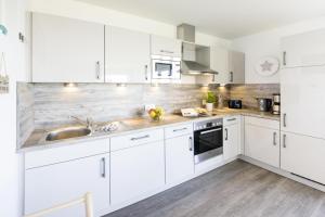 a white kitchen with white cabinets and a sink at Ostseeliebe in Olpenitz