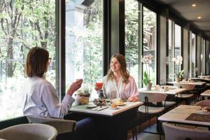 Dos mujeres sentadas en una mesa en un restaurante en JR Hotels Bologna Amadeus, en Bolonia