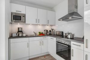 a white kitchen with white cabinets and a microwave at Blue Heaven in Olpenitz
