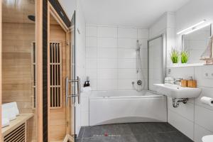 a white bathroom with a tub and a sink at Blue Heaven in Olpenitz