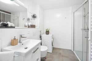 a white bathroom with a sink and a toilet at Marina Sunrise in Olpenitz