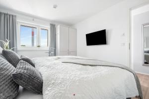 a white bedroom with a bed and a flat screen tv at Marina Sunrise in Olpenitz