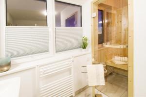 a bathroom with white cabinets and windows and a chair at Heimathafen in Olpenitz