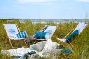 zwei Stühle sitzen im Gras nahe dem Strand in der Unterkunft Ab ans Meer in Olpenitz