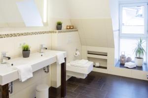 a white bathroom with two sinks and a toilet at Penthouse am Glockenturm in Flensburg
