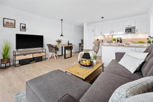 a living room with a gray couch and a kitchen at Hafen & Meer in Olpenitz