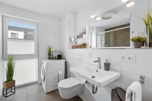 a white bathroom with a sink and a toilet at Hafen & Meer in Olpenitz