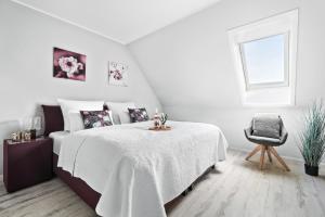 a white bedroom with a bed and a chair at Luv in Osterhever