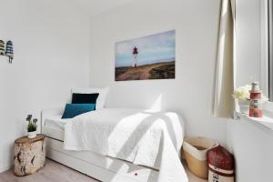 ein weißes Schlafzimmer mit einem Bett und einem Leuchtturm in der Unterkunft Ferienwohnung Freigeist, App 16 Emmelsbüll in Emmelsbüll-Horsbüll