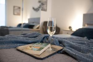 a glass of wine and a book on a bed at Pequeno Secreto in Olpenitz