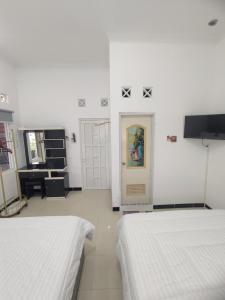 ein weißes Zimmer mit 2 Betten und einer Tür in der Unterkunft Griya Adevita Sidoarum in Sleman