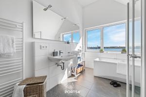 uma casa de banho branca com um lavatório, uma banheira e janelas em Sea Bay em Olpenitz