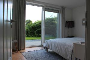 Schlafzimmer mit einem Bett und einer Glasschiebetür in der Unterkunft Strandfrieden in Flensburg