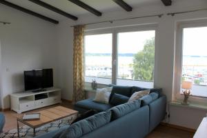 a living room with a blue couch and a large window at Strandfrieden in Flensburg