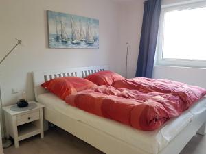 um quarto com uma cama com lençóis vermelhos e uma janela em Ferienhaus Ostseesegler em Glücksburg