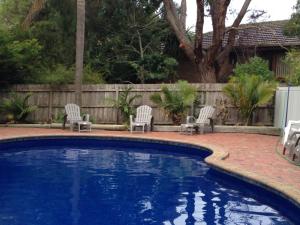 uma piscina com cadeiras e uma cerca em Coachman Motel and Holiday Units em Cowes