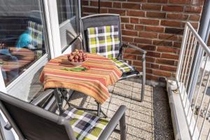 a table and chairs on a porch with a bowl of fruit at Urlaub mit Ostseeblick, Schwimmbad, Sauna & direkte Strandlage in Kronsgaard