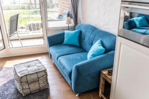 a blue couch in a living room with a window at Urlaub mit Ostseeblick, Schwimmbad, Sauna & direkte Strandlage in Kronsgaard +21 photos