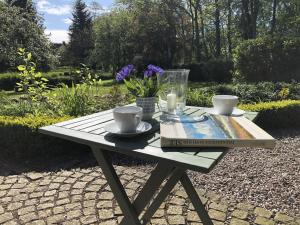 a picnic table with two cups and a book on it at Kate am Barkenhof in Ekenis