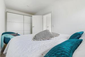- une chambre blanche avec un lit et des oreillers bleus dans l'établissement Lütte Deern, à Glücksburg