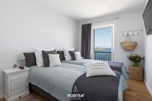 a white bedroom with a bed and a window at Ocean Lounge in Olpenitz